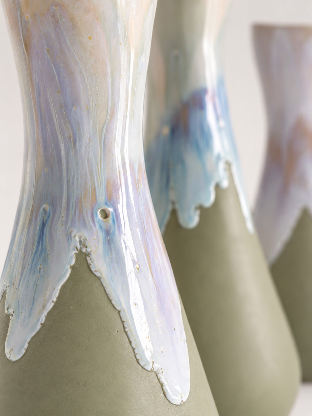 Detail of the pearlescent glaze flowing over the sage-green body of CALASSI AYA · VMR vessels