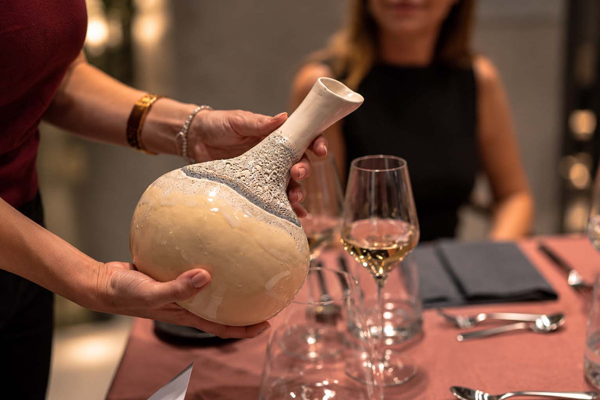 Pouring ZEN Chardonnay from the CALASSI vessel at a dinner table